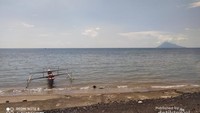 Perahu nelayan dengan latar belakang Gunung Manado Tua