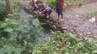 Seorang anak mengikuti sang ibu menghanyutkan bunga