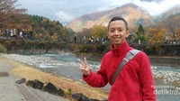Sungai dan pengunjung yang lalu-lalang di belakang
