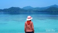 Memandang hamparan gradasi laut biru dan bukit hijau di sepanjang batas laut