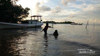 Anak-anak kecil bermain di pantai dekat Dermaga Mrican