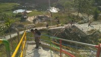 Pemandangan kolam serta beberapa pengunjung yang hendak menaiki tangga menuju puncak.