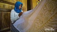 Pengrajin batik sedang nyanthing kain batik