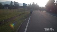 Jalur jalan raya yang dihiasi dengan pemandangan perbukitan di kejauhan