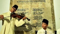 Partitur Lagu Indonesia Raya yang melatar belakangi diorama WR Supratman yang sedang memainkan biola mengiringi lagu Indonesia Raya