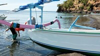Pantai berbatu-batu hitam dan laut berwarna biru jernih