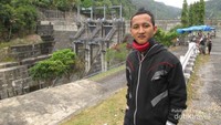 Berfoto di depan bendungan