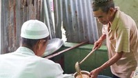 Pengurus masjid membagikan bubur.