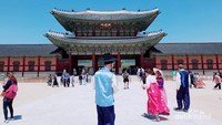Wisatawan baik laki-laki dan perempuan memakai pakaian khas Korea Selatan di Gyeongbuk Palace.
