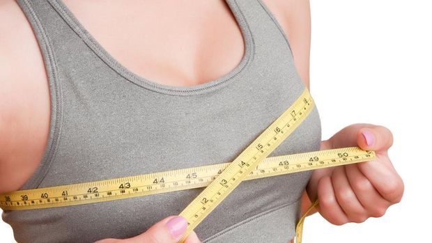 Plus size fat mature woman wearing bra with measure tape measuring her chest under breast. Closeup part of female body. Bosom, brafitting and underwear concept.