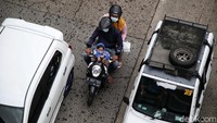 Pengendara sepeda motor berusaha menyelinap di antara mobil yang terjebak macet.