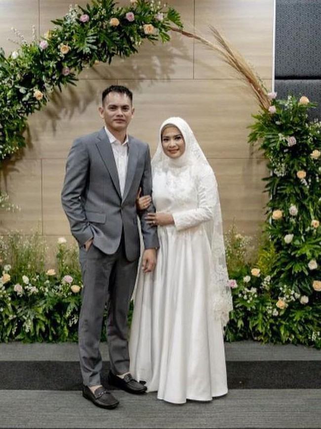 Ikke Nurjanah tampil sederhana dengan gaun putih dan hijab simpel di hari pernikahannya. Gaun berpotongan A-line dengan detail bordir dan lace rancangan Defrico Audy.  Foto: Instagram/@ikkenurjanah0518, @zoie.pictures
