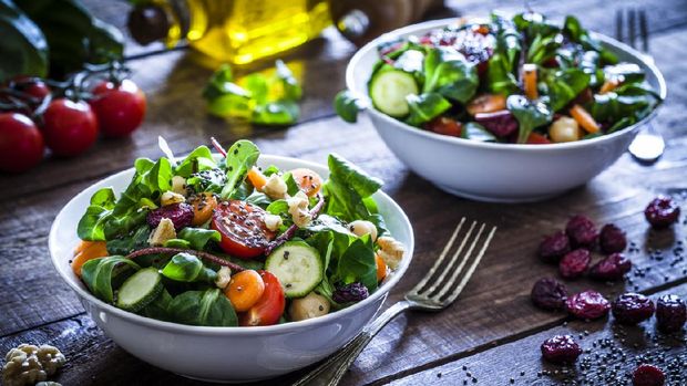 Two healthy salad bowls with chia seeds shot on rustic wooden table. The ingredients included for the preparation are chia seeds, lettuce, cherry tomato, carrot, arugula, cucumber and avocado. Some vegetables for salad preparation are scattered on the table. DSRL studio photo taken with Canon EOS 5D Mk II and Canon EF 100mm f/2.8L Macro IS USM