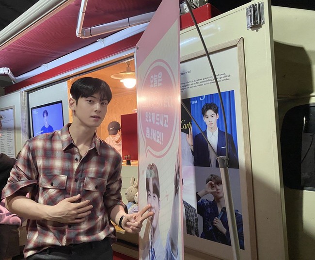 Food truck Cha Eun Woo kembali terparkir di lokasi syuting drama Korea True Beauty. Meski kali ini agak meleset, Cha Eun Woo tetap menunjuk lubang hidungnya yang terpampang di banner. Fotonya ini bahkan diunggah di akun Twitter grup ASTRO. Foto: Instagram