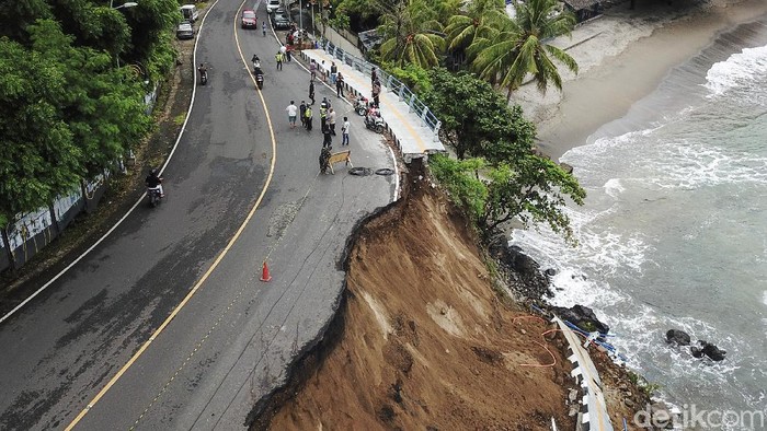 Sejumlah petugas berjaga di pinggir tebing jalan yang longsor di Senggigi, Kecamatan Batulayar, Lombok Barat, NTB, Sabtu (6/2/2021). Longsor terjadi karena intensitas hujan yang cukup tinggi Sabtu (6/2) dini hari menyebabkan jalan wisata Senggigi yang menghubungkan Kabupaten Lombok Barat dan Kabupaten Lombok Utara amblas sepanjang 45 meter dengan kedalaman 11 meter. ANTARA FOTO/Ahmad Subaidi/foc.