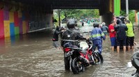 Banjir di kolong tol dimanfaatkan warga untuk menawarkan jasa penyeberangan menggunakan gerobak.