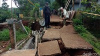 Jalan desa tersebut terbelah, begitu juga dengan saluran air yang hancur. 