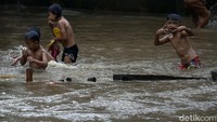 Banjir ini dimanfaatkan oleh anak-anak untuk bermain meski air sungai berwarna coklat dan penuh sampah.