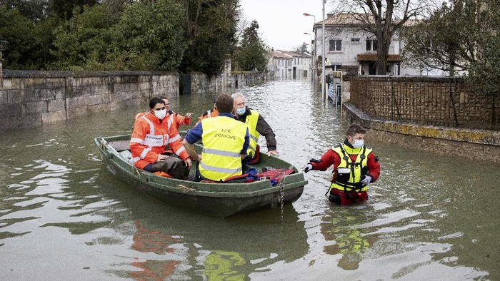A woman pulls a small boat in a flooded street of Le Gond-Pontouvre, near Angouleme, southwestern France, Friday, Feb 5, 2021. In southern France, waters are starting to recede after the worst flooding in 40 years swelled the Garonne River between Bordeaux and Toulouse. (AP Photo/Yohan Bonnet)