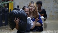 Warga pun nekat menerobos air banjir dengan berjalan kaki.