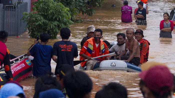 BANJIR DI JALAN RAYA PANTURA KARAWANG Seorang warga menggendong anaknya melintasi banjir di ruas jalan Pantura, Jalan Ahmad Yani, Cikampek, Karawang, Jawa Barat, Minggu (7/2/2021). Hujan yang terjadi di wilayah tersebut mengakibatkan sejumlah ruas jalan tergenang banjir dan menimbulkan kemacetan. ANTARA FOTO/M Ibnu Chazar/rwa.