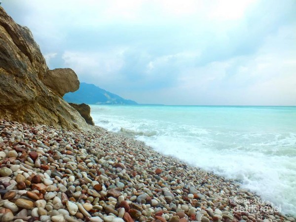 pantai kolbano yang unik dengan batu berwarna di tepi pantainya.