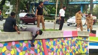 Pegawai Dinas ESDM Provinsi Riau disela pengecatan dinding saluran parit.