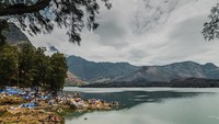 Tepian danau Segara Anak yang dipenuhi tenda-tenda dengan pemndangan gunung Baru Jari