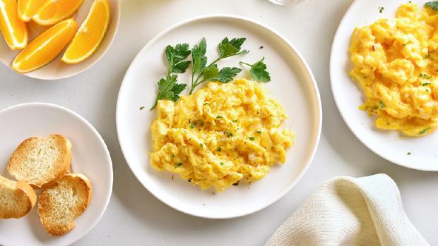 Tasty diet dish for breakfast or lunch. Scrambled eggs on plate over white stone background. Healthy food. Top view, flat lay