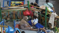 Dengan beralaskan tikar dan terpal, sejumlah warga yang mengungsi di kolong jembatan tampak beristirahat di sana.