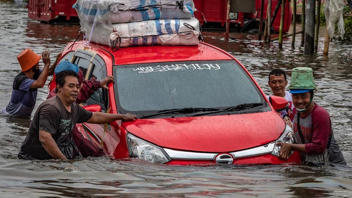 Banjir di Sepanjang Pantura Sejumlah warga mendorong mobil mogok akibat menembus jalur Pantura Jalan Raya Kaligawe - Genuk yang terendam banjir di Genuk, Semarang, Jawa Tengah, Senin (8/2/2021). Banjir akibat intensitas hujan tinggi merendam jalur tersebut sejak Sabtu (6/2) dengan ketinggian bervariasi sekitar 30 cm - 1,2 meter sehingga menyebabkan lalu lintas dari Kota Semarang menuju Kabupaten Demak maupun sebaliknya terganggu. ANTARA FOTO/Aji Styawan/foc.