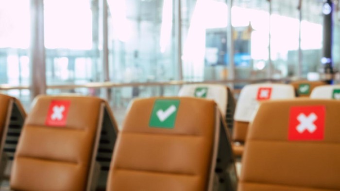 Social distancing, Blurred image of empty chairs in an airports departure area marked with symbols regarding social distancing protocol to prevent the spreading of novel corona virus, COVID-19