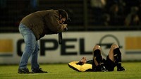 Seorang jurnalis foto mengambil gambar pemain bola di tengah lapangan. Betapa pun sulitnya tugas yang diberikan, seperti diminta mengupas informasi soal mafia bola di tubuh PSSI, seorang jurnalis diwajibkan untuk mencobanya lebih dulu walau tahu itu pekerjaan sulit. Getty Images/Tim de Waele  