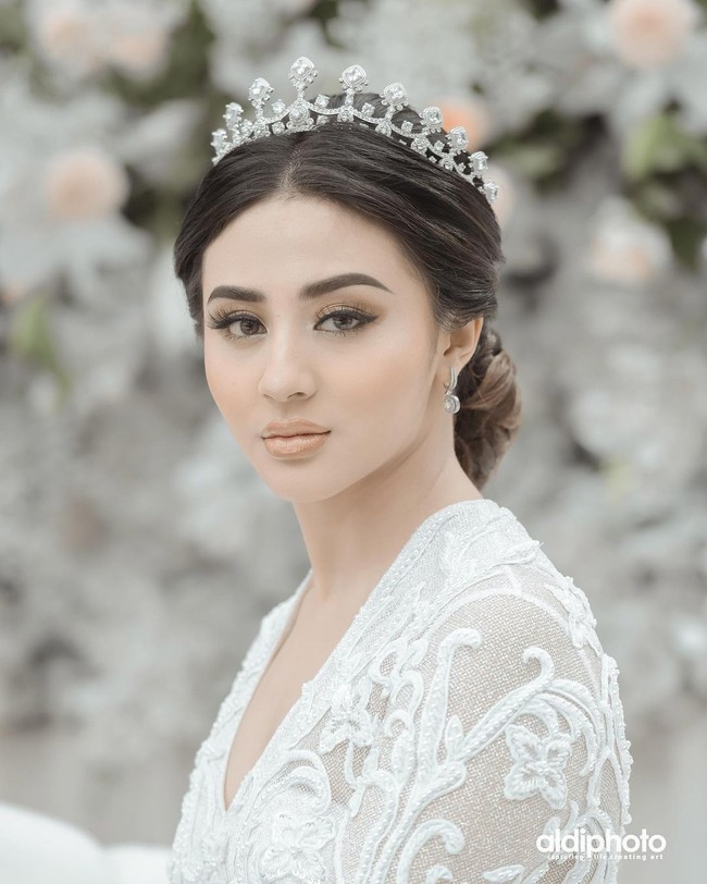 Gaun tersebut hadir dengan neckline V yang menginjeksikan kesan seksi. Tampak sebuah mahkota iku menyempurnakan gaya Margin Wieheerm di hari bahagianya. (Foto: Aldi Photography via Instagram/@marginw)