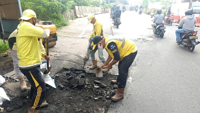 Petugas dari Dinas Bina Marga DKI Jakarta, memperbaiki lobang di Jalan Noer Ali, Kalimalang Raya, Pondok Bambu, Jakarta Timur.