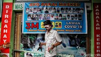 Warga beraktivitas dengan memakai masker di depan gerbang kawasan RW Zona Merah, Sunter Jaya, Jakarta Utara, Selasa (9/1/2021).