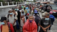 Warga tampak mengenakan masker saat mengantre untuk mendapatkan nasi gratis.