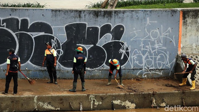 Sungai Ciliwung di kawasan Kampung Melayu, Jakarta Timur sempat meluap. Usai surut, petugas kebersihan melakukan bersih-bersih lumpur yang berada di bantaran Sungai Ciliwung.