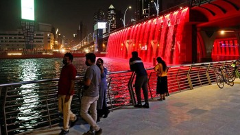 Warga Uni Emirat Arab mengamati Dubai Canal Waterfall yang disinari cahaya merah, di mana Planet Mars memang dijuluki Planet Merah. Foto: AP/Kamran Jebreili