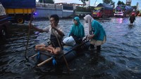 Warga menaiki perahu rakit menerobos jalan yang tergenang banjir di jalan jalur Pantura Desa Jati Wetan, Kudus, Jawa Tengah, Selasa (9/2/2021). Banjir dengan ketinggian hingga 50cm sejak Sabtu (6/2) lalu itu menyebabkan kemacetan dari arah Kudus menuju Semarang. ANTARA FOTO/Yusuf Nugroho.