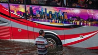 Sebuah bus menembus jalan yang banjir di jalur Pantura Kaligawe, Semarang, Jawa Tengah, Selasa (9/2/2021). ANTARA FOTO/Aji Styawan.
