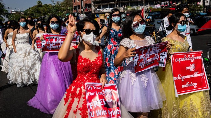 1301216062 YANGON, MYANMAR - FEBRUARY 09: Protesters cover themselves with large plastic sheets to protect themselves from possible water canon use against them on February 09, 2021 in Yangon, Myanmar. Myanmar declared martial law in parts of the country, including its two largest cities, as massive protests continued to draw people to the streets a week after the country's military junta staged a coup against the elected National League For Democracy (NLD) government and detained de-facto leader Aung San Suu Kyi. Police fired rubber bullets, tear gas, and water cannon to disperse protesters at demonstrations across the country, and at least two people were in critical condition from the injuries sustained. (Photo by Hkun Lat/Getty Images)