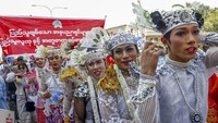 Massa pria dan wanita berdemonstrasi dengan mengenakan pakaian tradisional. 