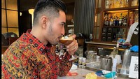 Mengenakan batik, Robby santai makan dessert dan menikmati minuman racikan bartender. Slurpp! Foto: Instagram robbypurba