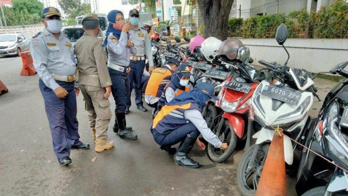 Petugas Suku Dinas Perhubungan Kota Jakarta Selatan melakukan operasi cabut pentil terhada sepeda motor yang diparkir di bahu jalan di Kalibata, Jakarta Selatan, Rabu (10/2/2021)