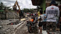 Warga hanya bisa menatap bangunan rumah itu diratakan dengan alat berat.