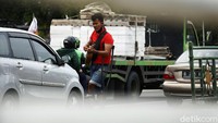 Dengan memakai tongkat, pengamen difabel menghibur lewat alat musik gitar ke sejumlah kendaraan yang terkena macet.