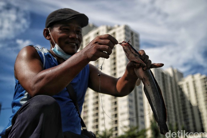 Salah satu keluarga etnis Tionghoa berbagi berkah jelang Imlek dengan melepas 8 drum besar ikan lele de dalam Kali Item, Sunter, Jakarta Utara.