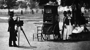 Seorang fotografer jalanan bekerja di Clapham Common, London, dengan stan keliling pada tahun 1877. Getty Images/John Thomson  