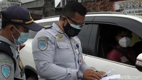Petugas memeriksa surat keterangan bebas Covid seorang pengendara.